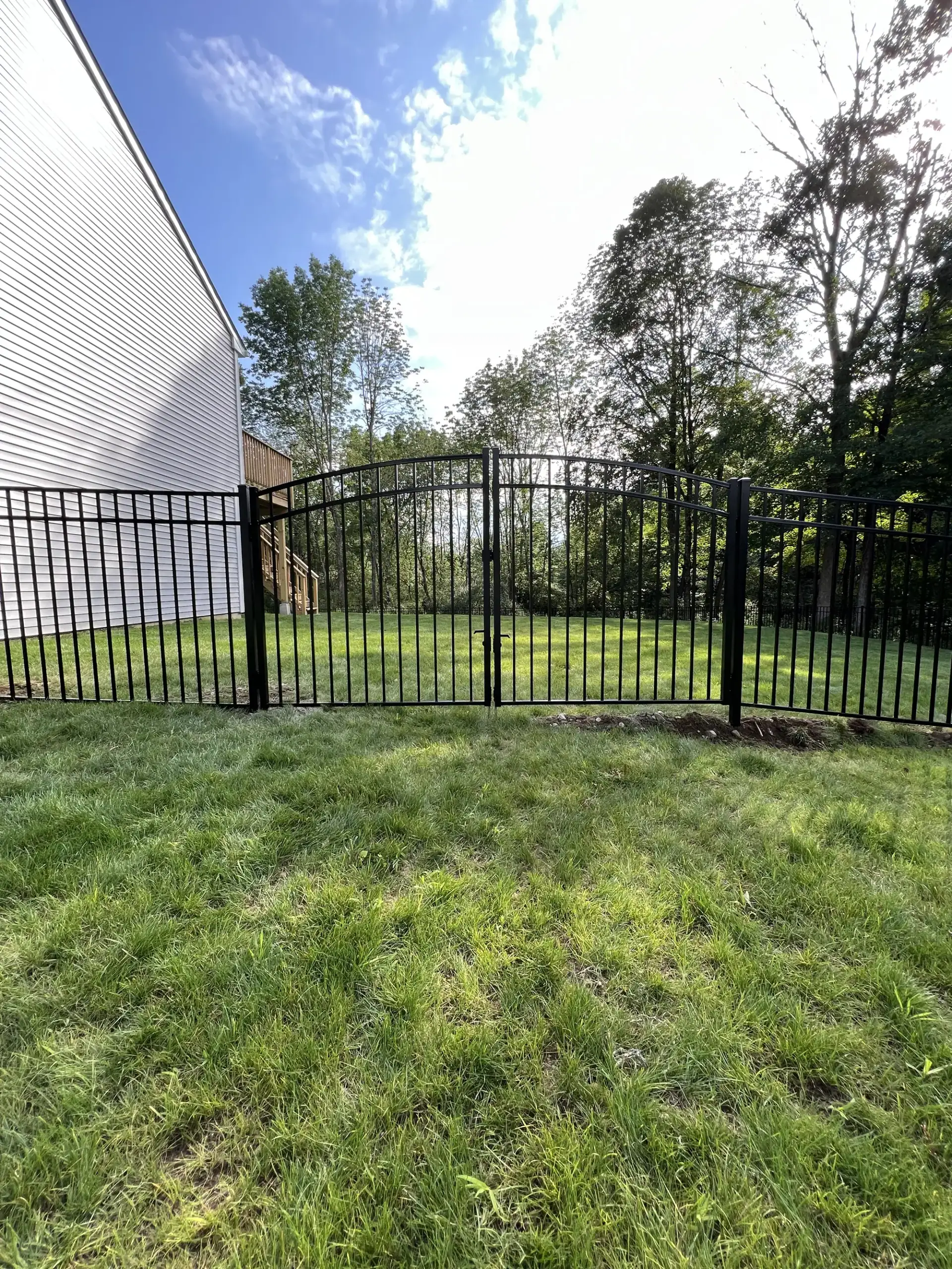 Black aluminum backyard fence with an arched gate