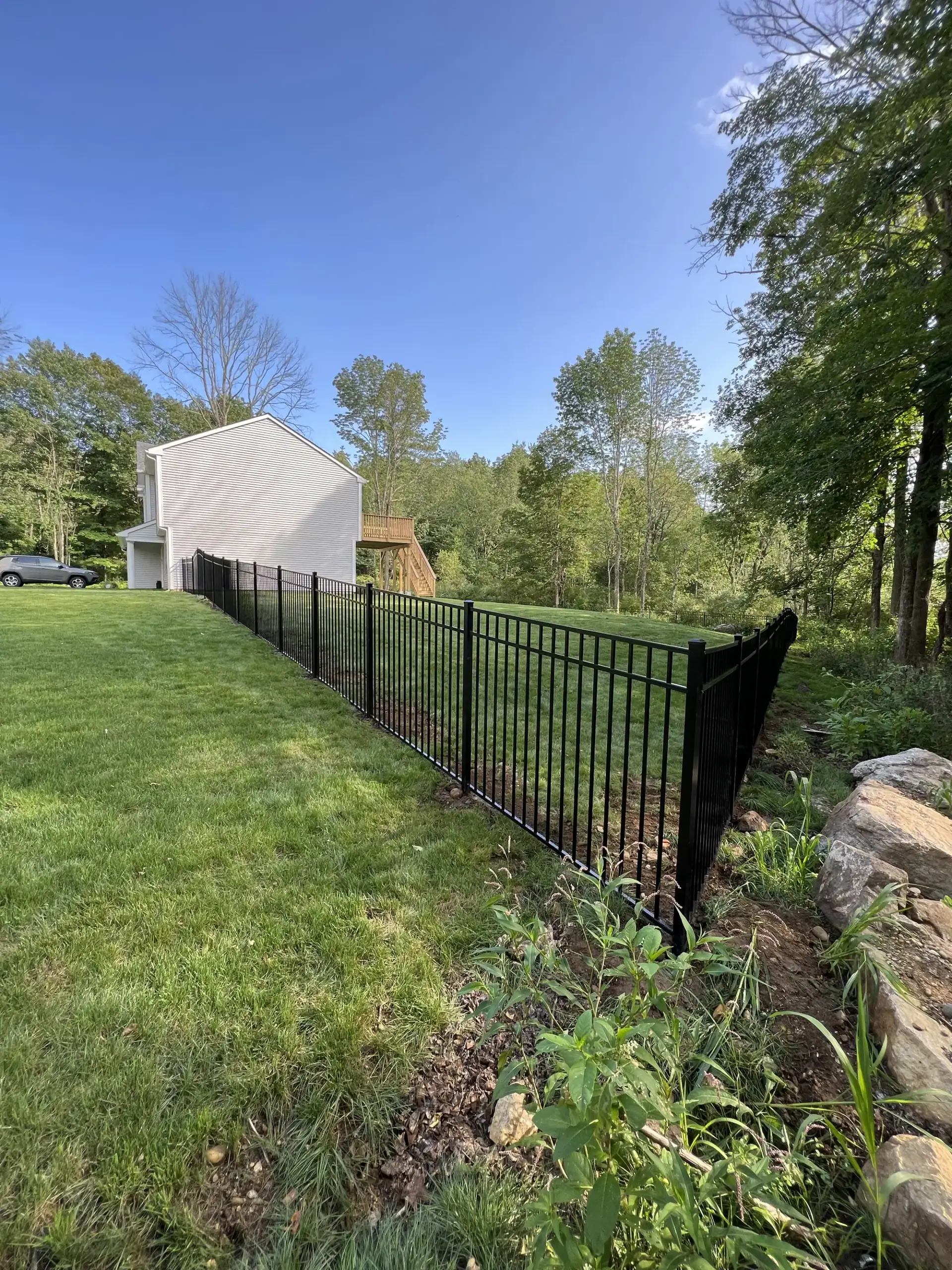 Black aluminum fence stepped down a sloped yard