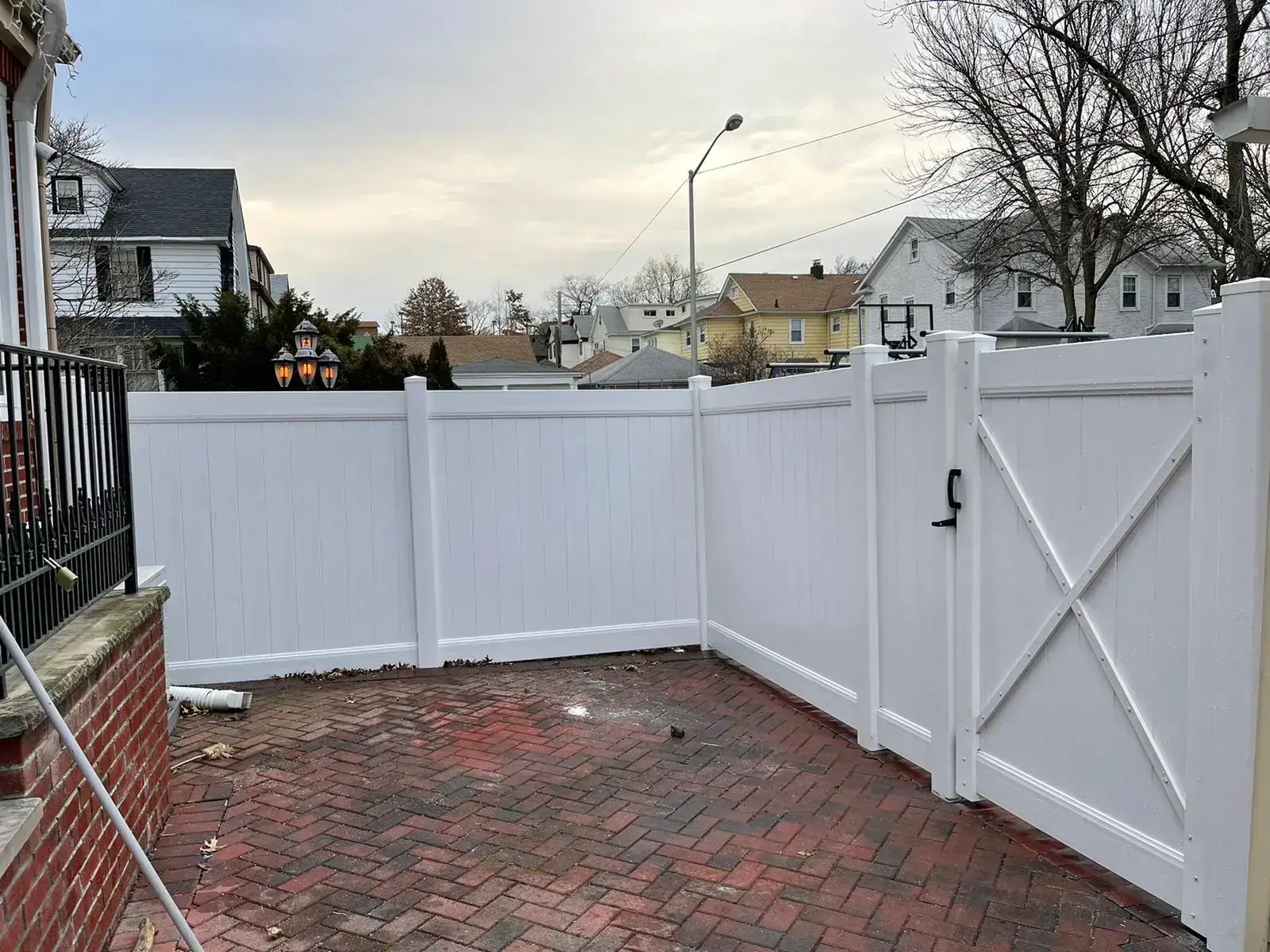 White vinyl fence and gate enclosing a brick patio
