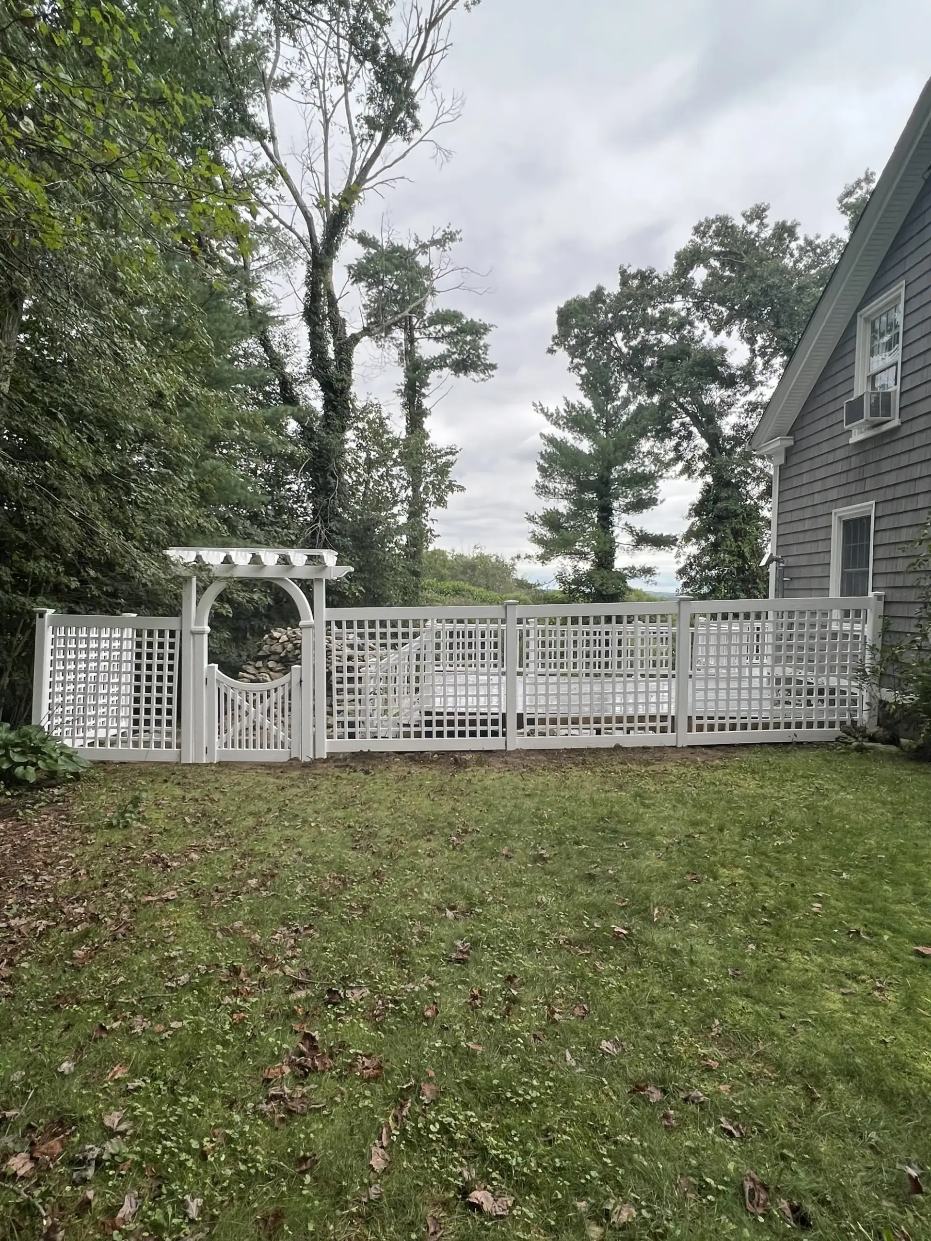 White vinyl picket fence with an arched arbor gate