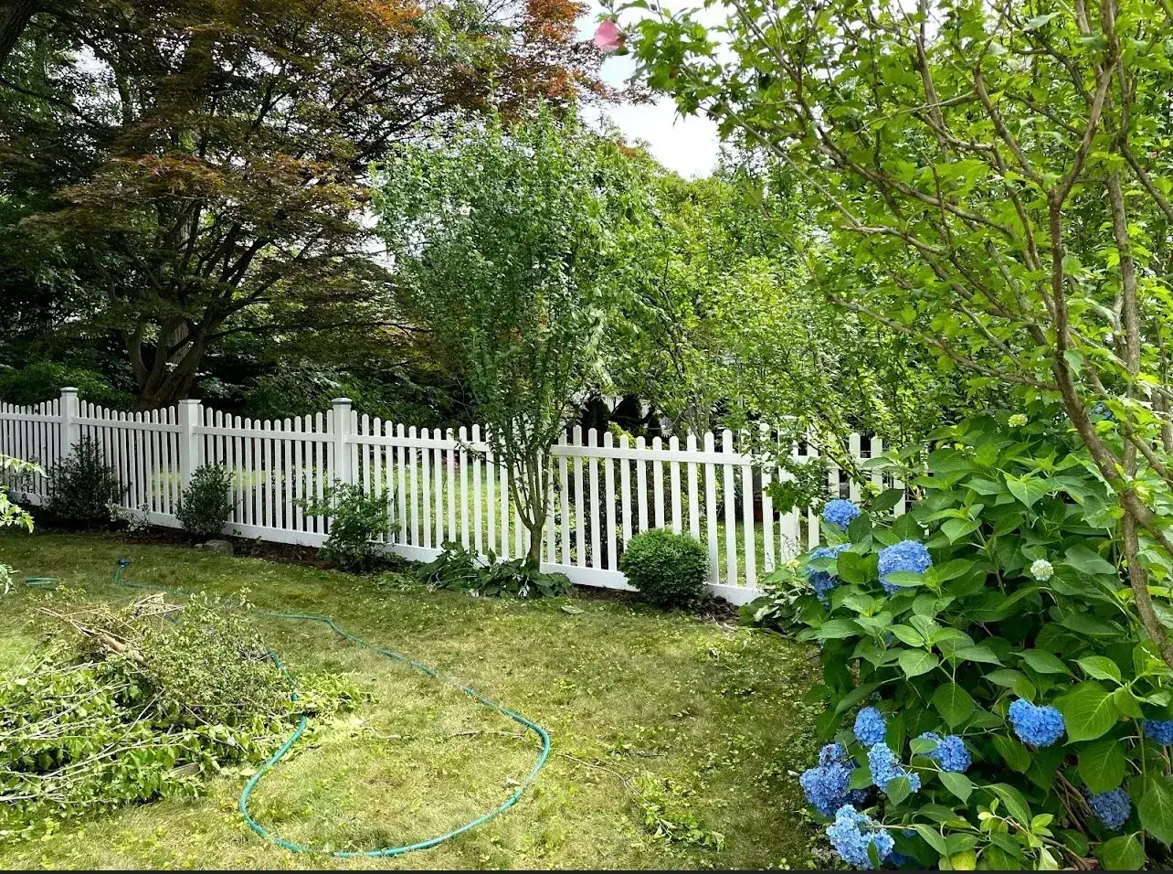 White vinyl picket fence framing a garden with hydrangeas