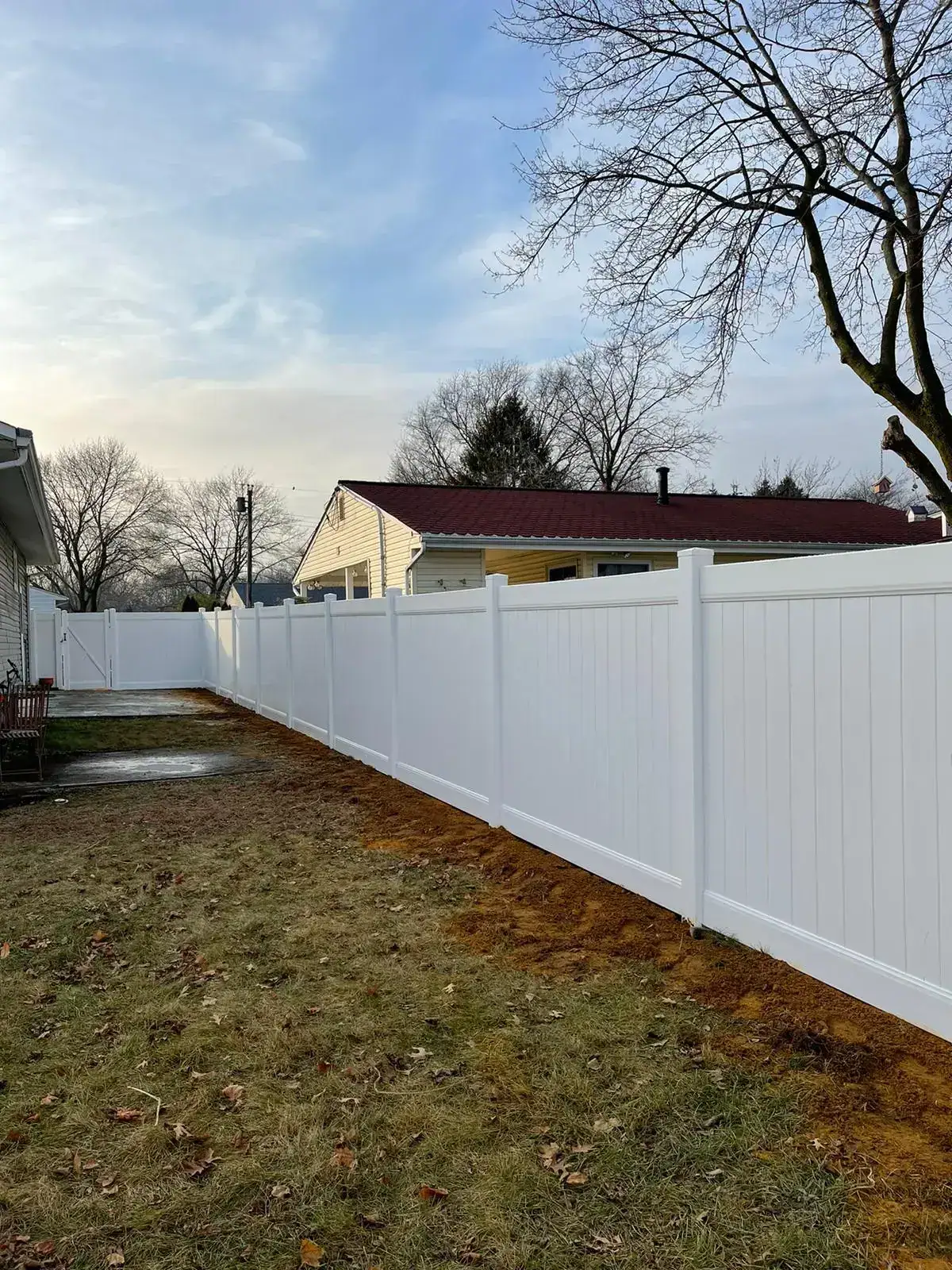 Long run of white vinyl privacy fence around a backyard