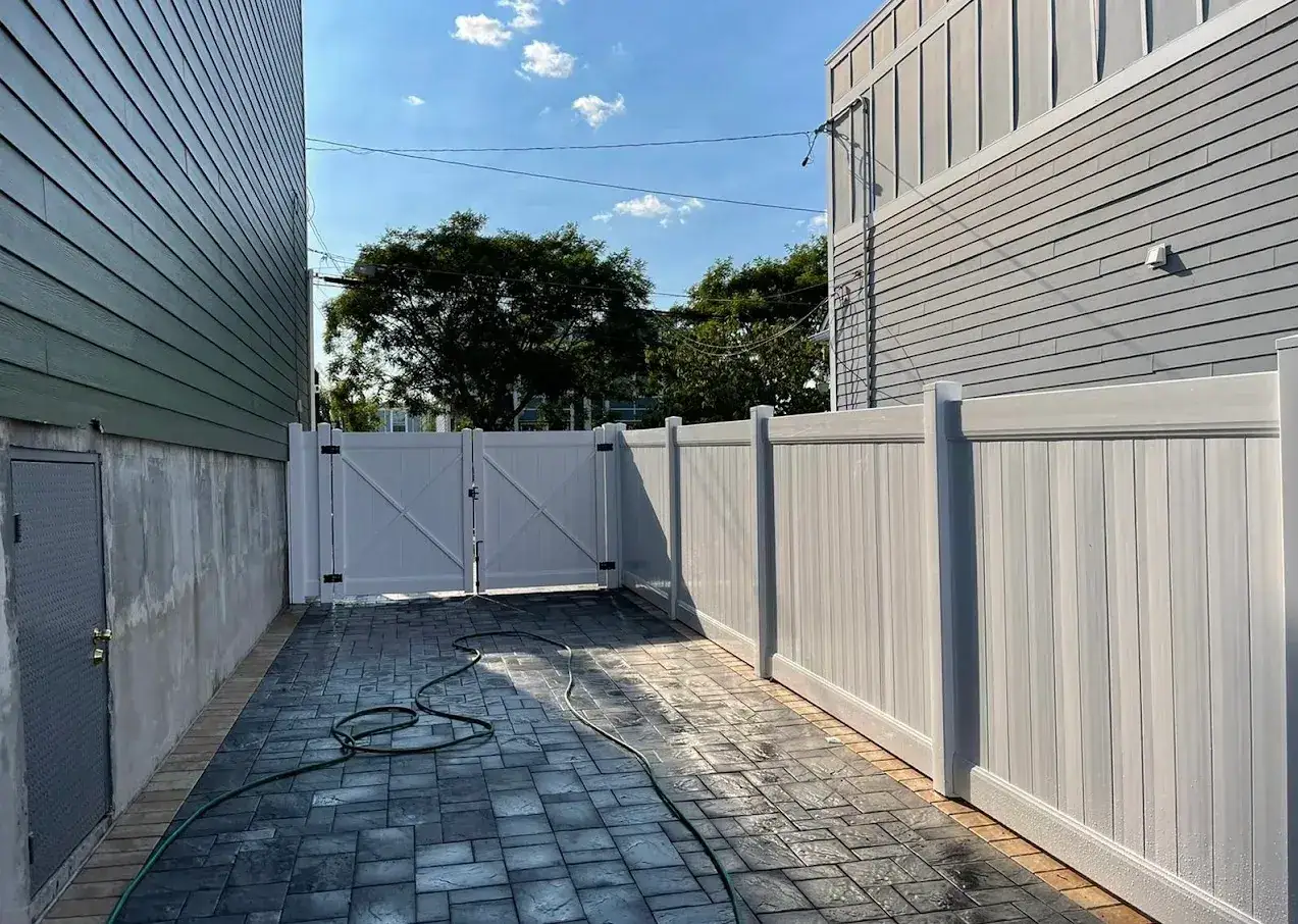 White vinyl privacy fence and gate beside a paver walkway