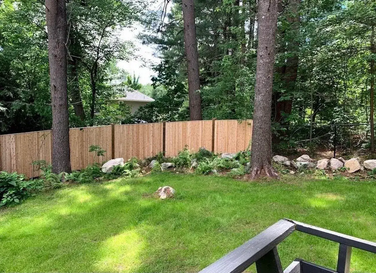 Wood privacy fence along the edge of a wooded backyard